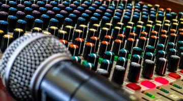 A microphone rests on a live sound mixing board